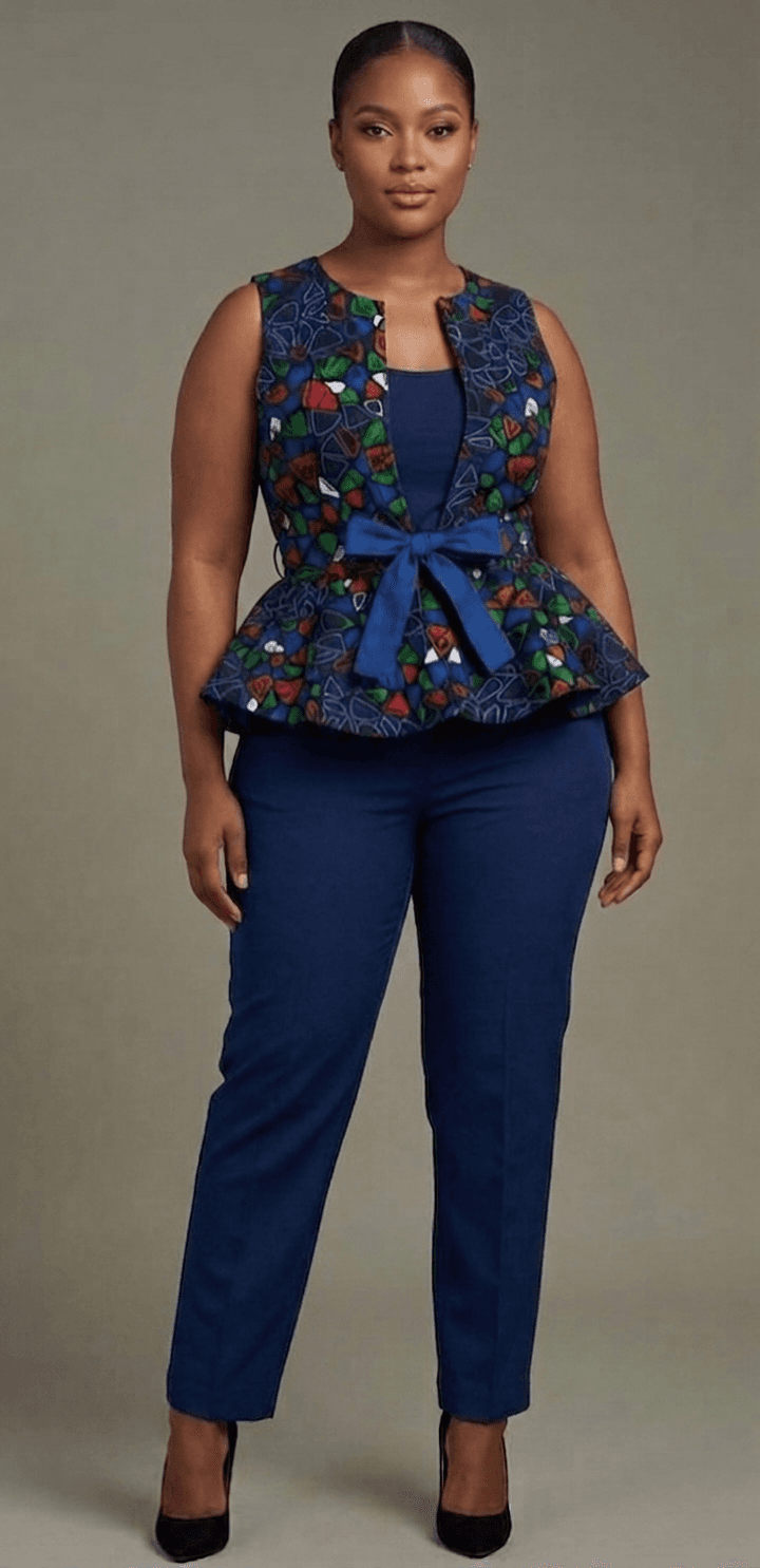 Tailored bespoke ensemble featuring a structured, jewel-toned geometric Ankara peplum vest secured with a prominent navy blue bow, layered flawlessly over a made-to-measure navy blue top and crisp trousers